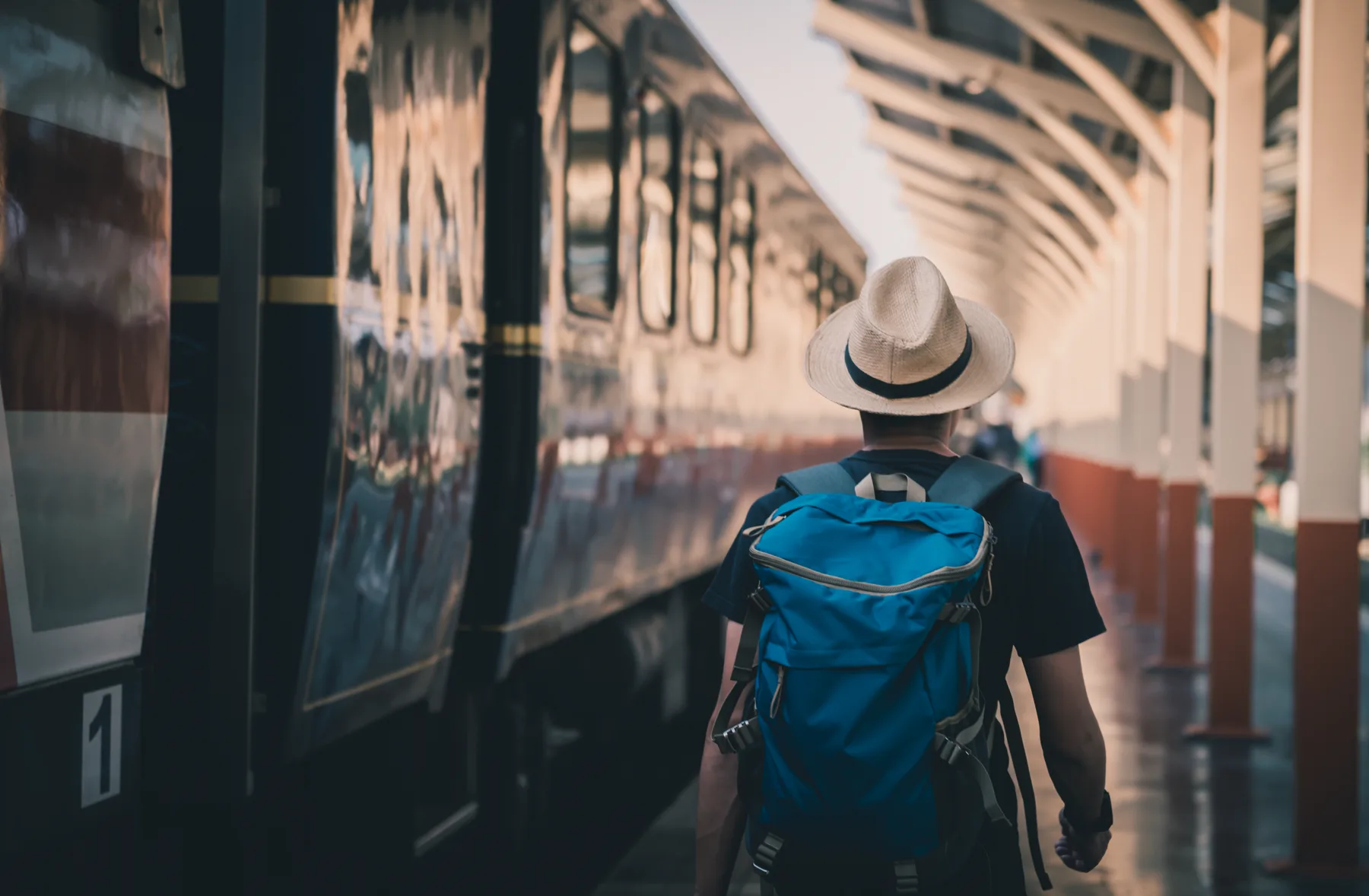 Viajero con mochila caminando hacia un tren